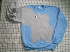 an elephant sweater laying on top of a bed