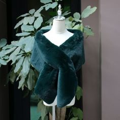 a mannequin wearing a green fur stole on top of a white dress form