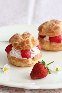 two pastries with strawberries on them sitting on a plate