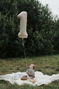 a baby sitting on a blanket with a balloon attached to it