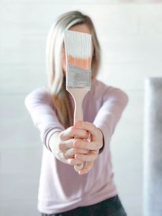 a woman holding a paint brush in her hand