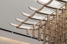 the ceiling is made up of wooden slats and suspended by metal rods with white chairs on them