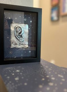 a black frame with a picture of a ear on top of a blue countertop