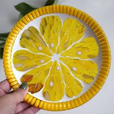 a hand holding a yellow paper plate with orange slices on it