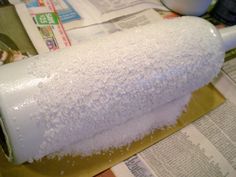 a roll of toilet paper sitting on top of a counter next to a cup and newspaper