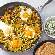 two fried eggs are in a pan with other food on the table next to it