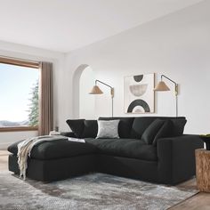 a living room with a large black couch and rug in front of a window that looks out onto the mountains