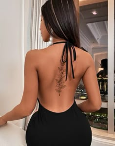 the back of a woman's body wearing a black swimsuit with flowers on it