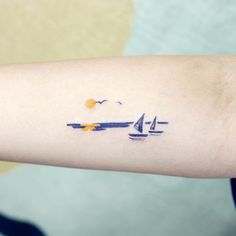 a person with a small tattoo on their arm that has sailboats in the water