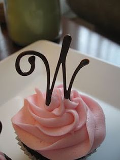 a cupcake with pink frosting and the letter w on it's side