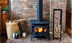 a wood burning stove sitting next to a pile of logs on top of a rug