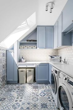 a laundry room with blue cabinets and tile flooring is shown in an attic - like space