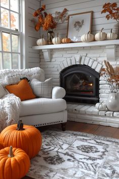 a living room with white furniture and pumpkins on the fireplace mantel in front of it