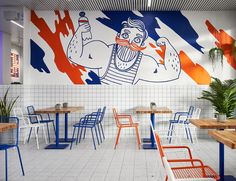 the interior of a restaurant with colorful painted murals on the walls and tables in front of them