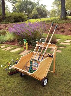 a wooden cart sitting on top of a grass covered field next to flowers and trees