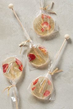 three lollipops wrapped in cellophane with strawberries on them