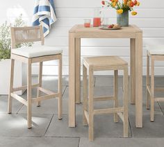 a table with two stools next to it and a vase full of flowers on the table