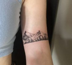 a woman's arm with a mountain scene tattoo on the left side of her arm