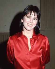 a woman in a red shirt smiling at the camera