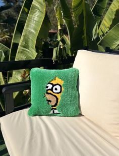 a green pillow sitting on top of a white chair next to a banana leaf covered tree