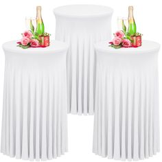 two round tables with white tablecloths and pink roses on them, each holding champagne bottles