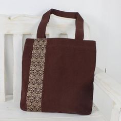 Keawpankanlaya of Thailand creates this pretty tote bag from 100% cotton in a rich mahogany shade. The front of the tote is embellished with traditional Thai yok dok embroidery in cream. The bag closes with a zipper to keep your belongings secure and an open interior pocket keeps small items close at hand. Brown Cotton Bag For Daily Use, Daily Use Brown Cotton Bag, Daily Brown Cotton Bag, Square Brown Canvas Bag, Brown Square Canvas Bag, Everyday Embroidered Brown Bags, Brown Embroidered Everyday Bags, Brown Cotton Shoulder Bag, Everyday Brown Embroidered Bags