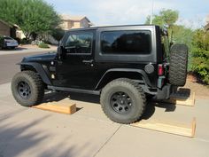 a black jeep parked on top of a wooden platform