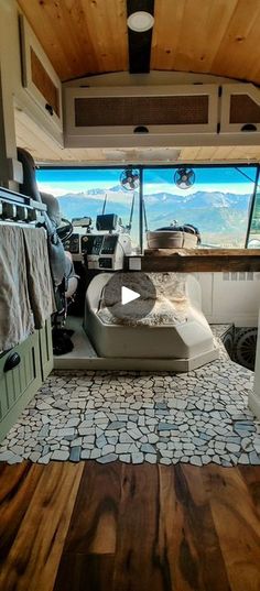 the inside of an rv with wood flooring and windows looking out at mountains in the distance