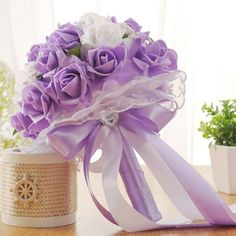 a bouquet of flowers sitting on top of a table next to a potted plant