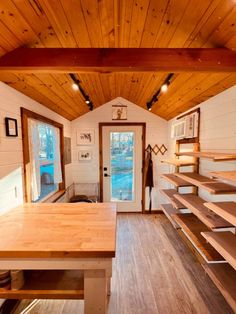 the inside of a tiny house with wood flooring and open shelving on the walls