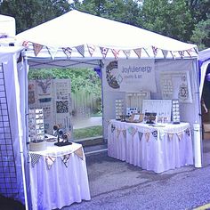 a tent set up on the side of a road with tables covered in white cloths