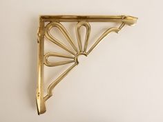 a gold metal shelf bracket on a white wall