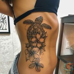 a woman's stomach with a turtle and flowers tattoo on the bottom of her body