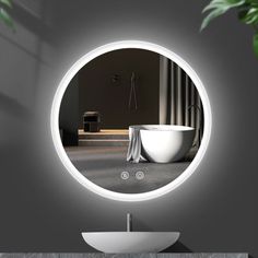 there is a round mirror on the wall above a sink with a white bowl in front of it