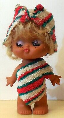 a small doll with blonde hair wearing a striped dress and headband on top of a table