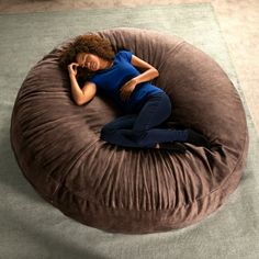 a woman laying on top of a brown bean bag chair