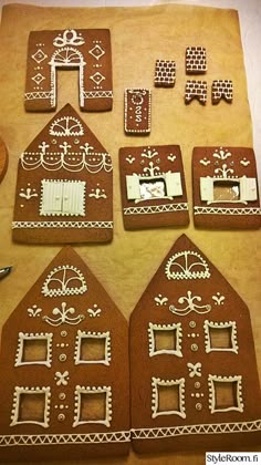 gingerbread houses are arranged on top of a sheet of wax paper and decorated with icing