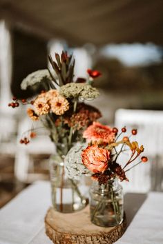 two vases filled with flowers sitting on top of a table