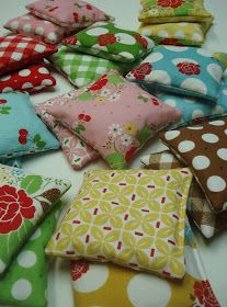 many different colored pillows sitting on top of a white table with polka dots and flowers