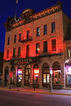 an old brick building is lit up with red lights on the front and side windows