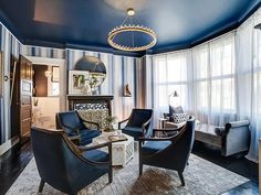 a living room with blue walls and furniture in the center, along with striped curtains