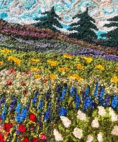 a field with flowers and mountains in the background is made out of crochet