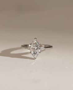 an engagement ring with a pear shaped diamond in the center on a white surface,