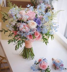 a bouquet of flowers sitting on top of a white table next to some blue and pink flowers