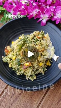 someone is cutting up some food on a black plate with purple flowers in the background