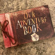 an adventure book sitting on top of a wooden table next to cookies and other items