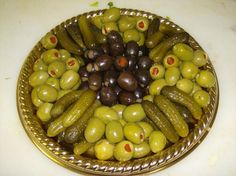 a bowl filled with olives and pickles on top of a white countertop