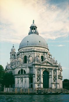 an old building with a dome on the top is next to a body of water