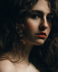 a close up of a woman with long hair and red lipstick looking at the camera