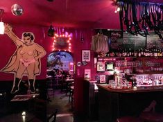 the interior of a bar with pink walls and lights hanging from the ceiling above it